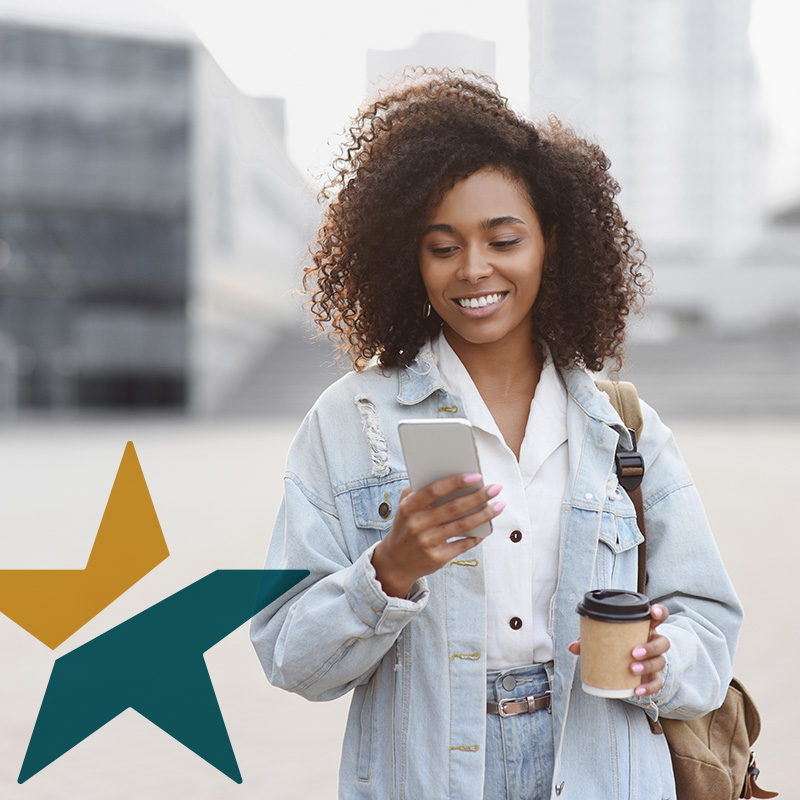 A woman holding a coffee looking at her phone