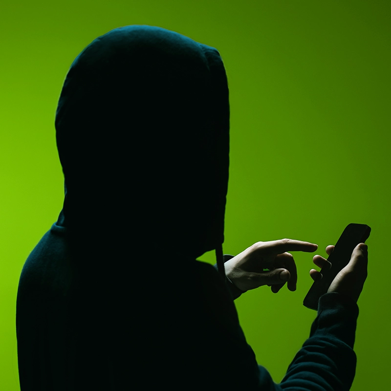 Hooded figure texting on phone