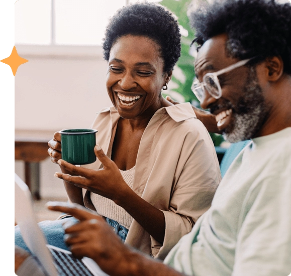 A couple smiling and looking at a laptop