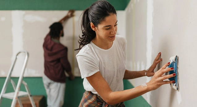A couple sanding and painting the wall in their new house